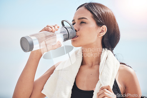 Image of Woman, runner and drinking water after fitness, training and wellness routine outdoor on blue sky background. Workout hydration and female thirsty after intense cardio, running and body exercise