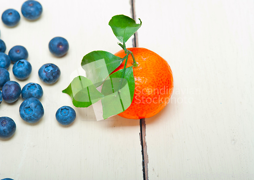 Image of tangerine and blueberry on white table