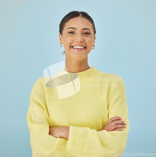 Image of Smile, portrait and woman in studio with arms crossed, fashion and youth mindset on blue background. Confidence, pride and happy face of girl with beauty, gen z style and excited positive attitude.