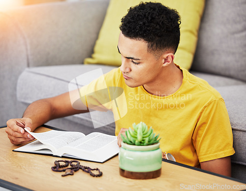 Image of Prayer, reading and bible with man in living room for worship, spiritual and Christian faith. Hope, God and belief with person praying with holy book at home for religion, thinking and gratitude