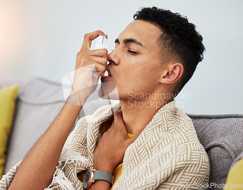 Image of Asthma, couch and man with inhaler for flu, cold or fever in a home living room with a blanket on a sofa. Healthcare, breath and young person with difficult symptoms, medical and sick in house lounge