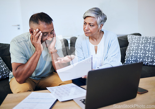 Image of Frustrated senior couple, documents and laptop in debt, financial crisis or struggle on sofa at home. Upset elderly man and woman in disagreement, argument or fight with finance, bills or expenses