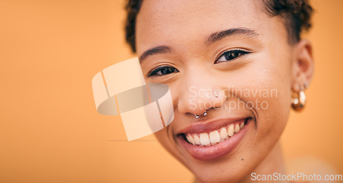 Image of Happy, woman and face closeup in studio with smile and confidence feeling cute. Orange background, young portrait and African female person with trendy, piercing and student fashion with gen z glow