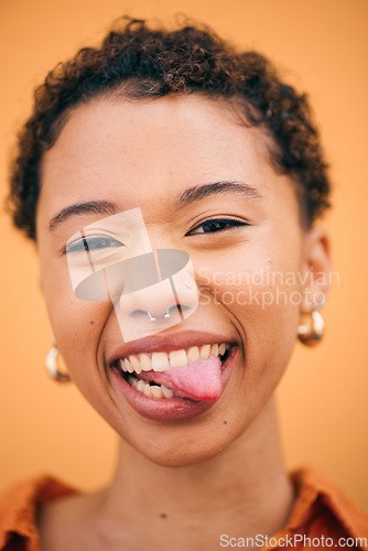 Image of Happy, woman and tongue out portrait in studio with smile and confidence feeling silly. Orange background, young and African female person with trendy, modern and student fashion with gen z piercing