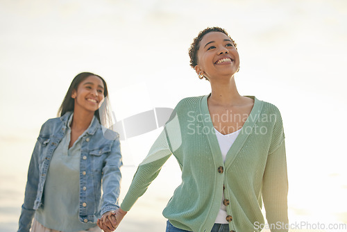 Image of Love, ocean and happy lesbian couple holding hands, walking together and sunset holiday adventure. Lgbt women, bonding and relax on beach vacation with romantic date, pride and smile on nature travel