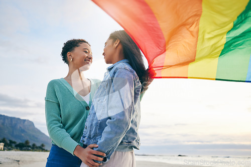 Image of Pride, flag and lesbian couple at the beach for travel, freedom and bond, care and happy in nature together. Rainbow, love and women on ocean vacation embrace lgbt, partner or gay, date or acceptance