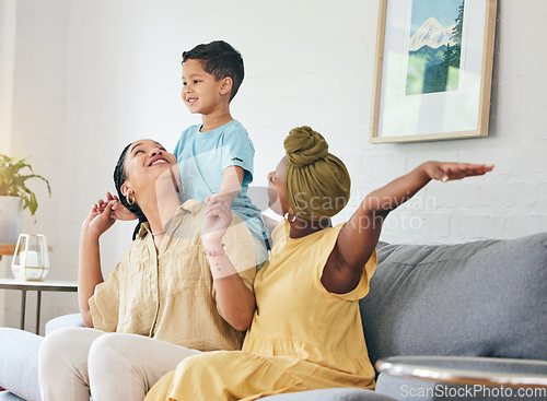 Image of Lesbian couple, gay family and boy child on a sofa with piggyback, game and fun in their home together. Love, lgbt and women mother in a living room with kid and shoulder, hug and playing in a house