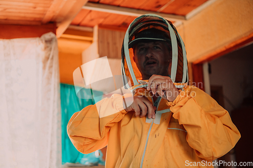 Image of Beekeeper put on a protective beekeeping suit and preparing to enter the apiary