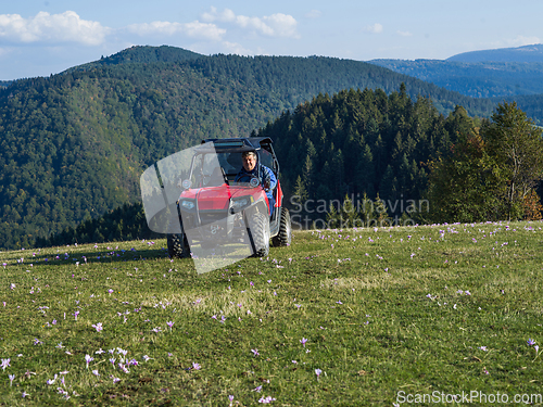 Image of A man driving a quad ATV motorcycle through beautiful meadow landscapes