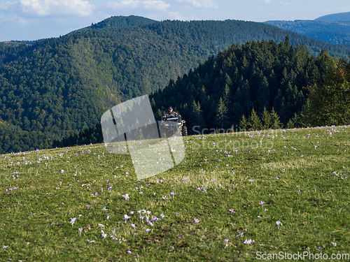 Image of A man driving a quad ATV motorcycle through beautiful meadow landscapes