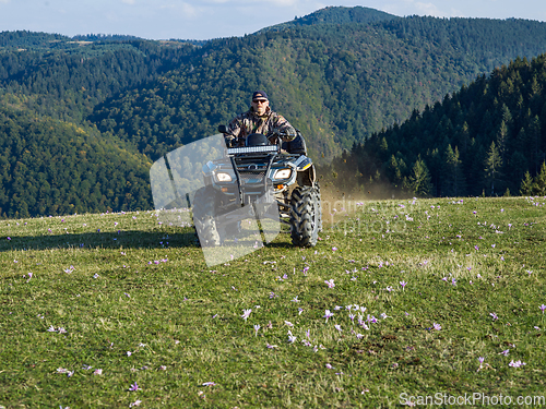 Image of A man driving a quad ATV motorcycle through beautiful meadow landscapes