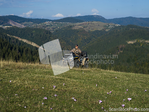 Image of A man driving a quad ATV motorcycle through beautiful meadow landscapes