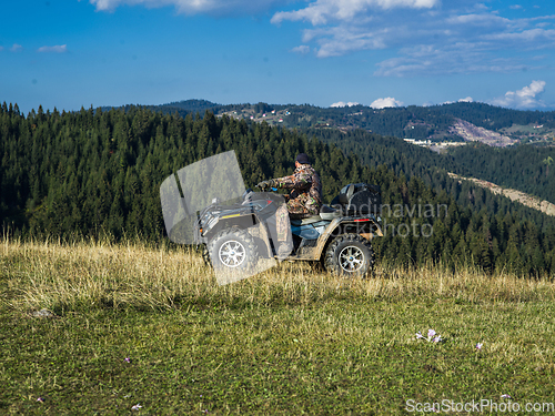 Image of A man driving a quad ATV motorcycle through beautiful meadow landscapes