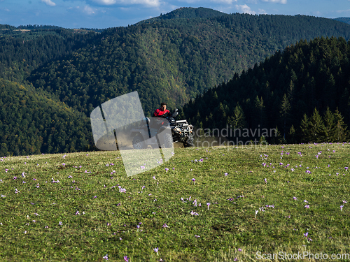 Image of A man driving a quad ATV motorcycle through beautiful meadow landscapes