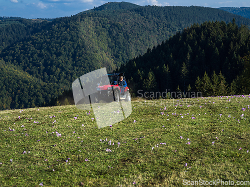 Image of A man driving a quad ATV motorcycle through beautiful meadow landscapes