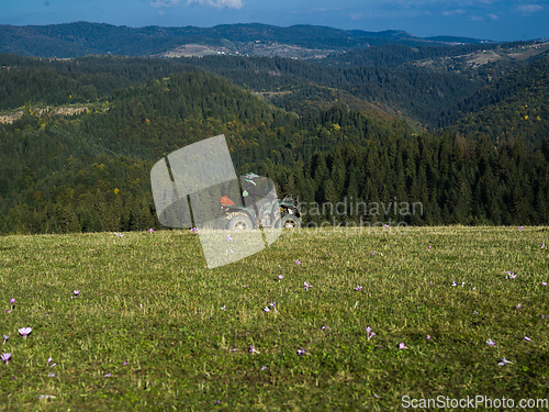 Image of A man driving a quad ATV motorcycle through beautiful meadow landscapes