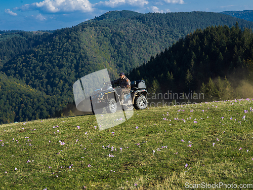 Image of A man driving a quad ATV motorcycle through beautiful meadow landscapes