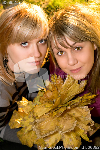 Image of Portrait of the two young blonde with autumn leaves