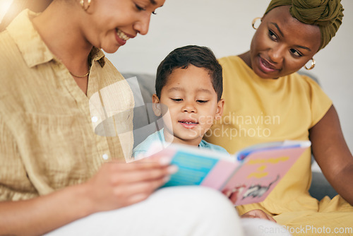 Image of Reading, gay family and child with a book on a home sofa for knowledge, education and learning. Adoption, lesbian or LGBT women or parents and kid together in a lounge with a story for quality time