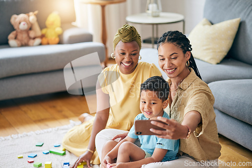 Image of Lesbian, women and son in home for selfie, smile or care with toys, post or blog on floor in living room. Mother, male kid and happy for gay love, bonding and memory on social network in family house