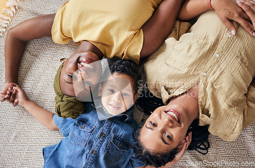 Image of LGBT, happy portrait and relax family, child or people care, smile and lesbian bond together, lying and on floor carpet. Mothers face, top view kid and non binary parents, homosexual mom or gay women