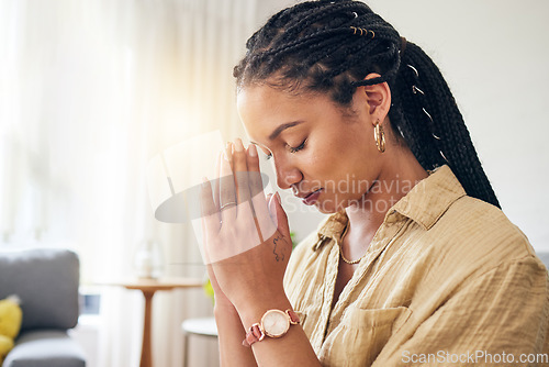 Image of God, worship and woman praying in her living room for hope, help or spiritual guidance in her home. Hands, pray and Christian female in prayer for blessing, grace and gratitude to Jesus Christ