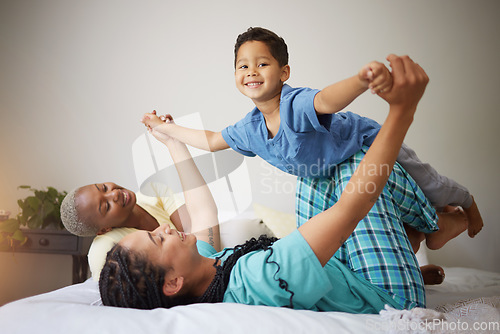 Image of Gay family, playing and child on a bed in a home bedroom for security, quality time and love. Adoption, lesbian or LGBTQ women or interracial parents lift a happy kid with fun game and support