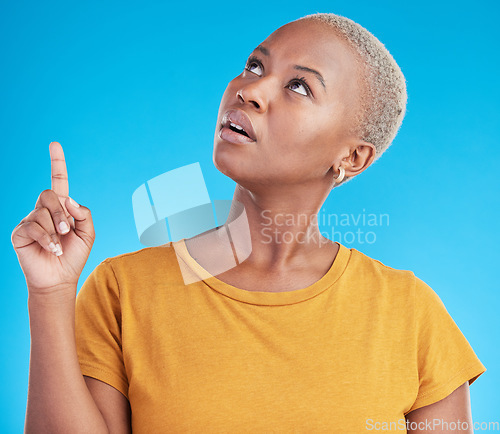 Image of Pointing up, discount or black woman in studio for mockup space, sale news or product offer on blue background. Doubt, confused or unsure person looking at a promotion, announcement or retail deal