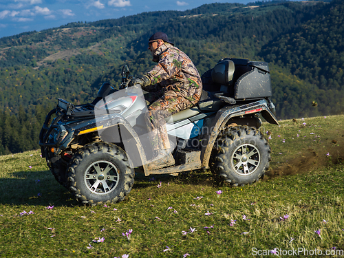 Image of A man driving a quad ATV motorcycle through beautiful meadow landscapes