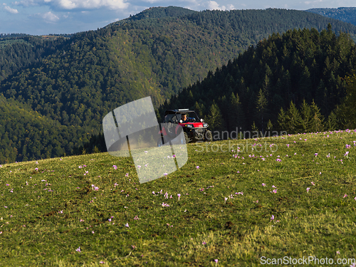 Image of A man driving a quad ATV motorcycle through beautiful meadow landscapes