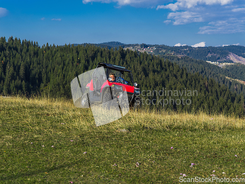 Image of A man driving a quad ATV motorcycle through beautiful meadow landscapes