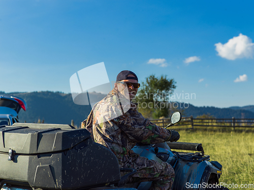 Image of A man driving a quad ATV motorcycle through beautiful meadow landscapes