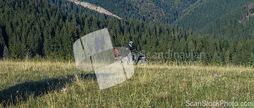 Image of A man driving a quad ATV motorcycle through beautiful meadow landscapes