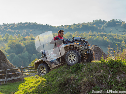 Image of A man driving a quad ATV motorcycle through beautiful meadow landscapes