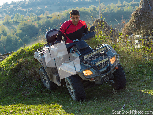 Image of A man driving a quad ATV motorcycle through beautiful meadow landscapes