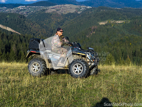 Image of A man driving a quad ATV motorcycle through beautiful meadow landscapes