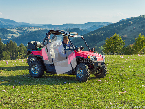 Image of A man driving a quad ATV motorcycle through beautiful meadow landscapes