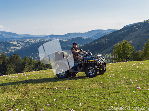 Image of A man driving a quad ATV motorcycle through beautiful meadow landscapes