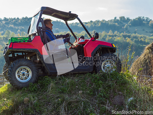 Image of A man driving a quad ATV motorcycle through beautiful meadow landscapes