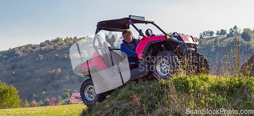 Image of A man driving a quad ATV motorcycle through beautiful meadow landscapes