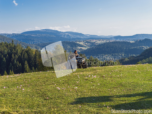 Image of A man driving a quad ATV motorcycle through beautiful meadow landscapes