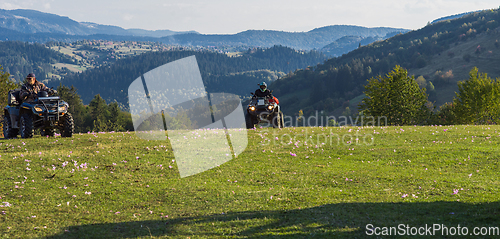 Image of A man driving a quad ATV motorcycle through beautiful meadow landscapes