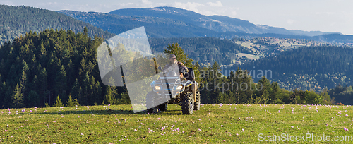 Image of A man driving a quad ATV motorcycle through beautiful meadow landscapes