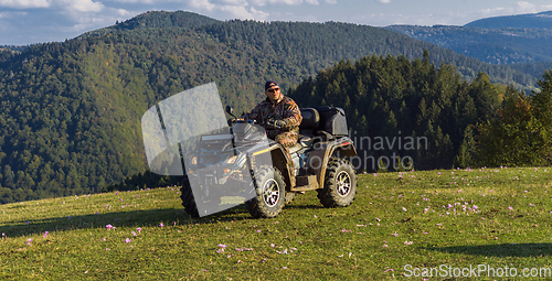 Image of A man driving a quad ATV motorcycle through beautiful meadow landscapes