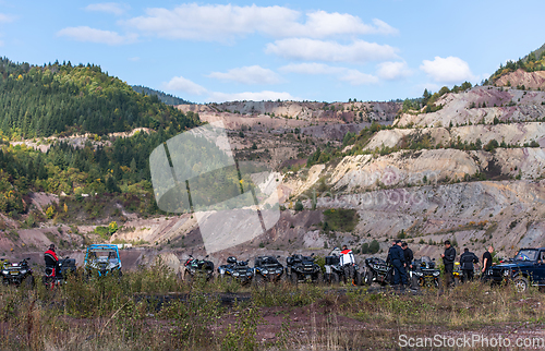 Image of A group of men on a social gathering are preparing to ride an ATV quad bike. People Ride together on a quad atv on muddy forest roads