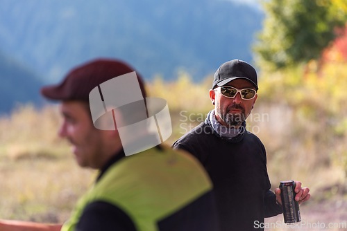 Image of A man in motorcycle gear with a cap and sunglasses holds a water bottle