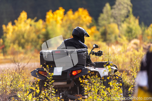 Image of A man driving a quad ATV motorcycle through beautiful meadow landscapes