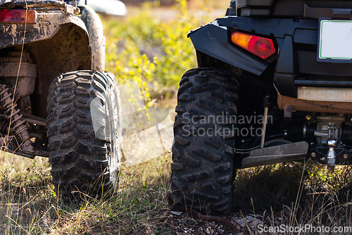 Image of Close-up tail view of ATV quad bike on dirt country road. Dirty wheel of AWD all-terrain vehicle. Travel and adventure concept.