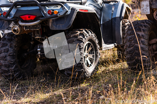 Image of Close-up tail view of ATV quad bike on dirt country road. Dirty wheel of AWD all-terrain vehicle. Travel and adventure concept.