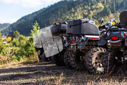 Image of Close-up tail view of ATV quad bike on dirt country road. Dirty wheel of AWD all-terrain vehicle. Travel and adventure concept.